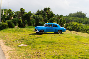 retro American car parked under the palm trees of Cuba