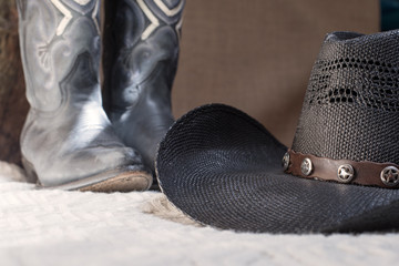 detail of black cowboy hat with blue boots on background