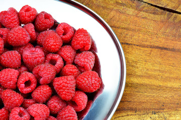 Obstkarte - Himbeeren am Serviertablett am Holztisch mit Textfreiraum
