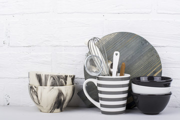 Simple modern kitchen still life in monochrome marble bowls, gray striped circle, round cutting board, ceramic  against a white brick wall. The horizontal