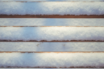 Bench in the park alley covered with snow
