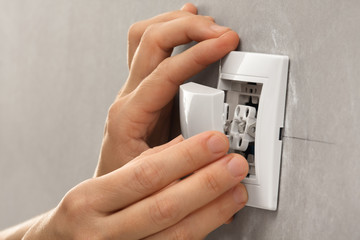 hands  of electrician installing light switch