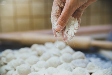 Man's hand sprinkling flour over a cutting board