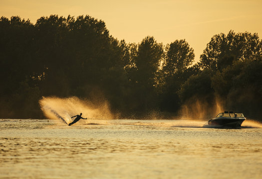 Man Wakeboarding On Lake Behind Boat