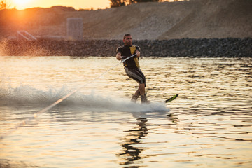 Man wakeboarding on lake at sunset