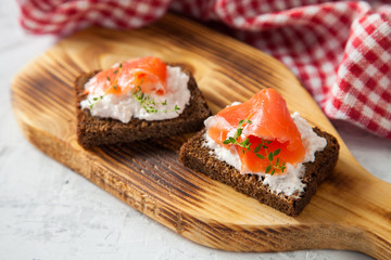 cheese, red fish and arugula sandwich on a board, selective focus, copy space