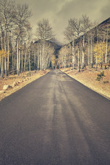 Retro color toned autumn road after the rain in Rocky Mountains National Park, Colorado, USA.