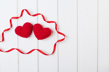 Two knitted hearts on white wooden background. Valentines day cards.