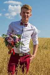 парень в поле с букетом