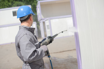 Man pressure washing a portacabin