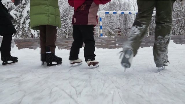 Winter shot of children skating on ice rink holding hands at countryside