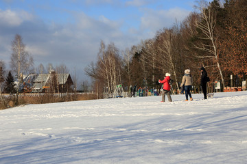 Trzy kobiety spacerują po śniegu w parku nad zamarzniętym jeziorem.