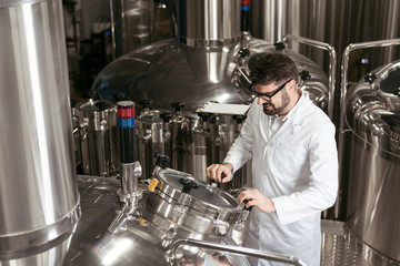 Satisfied man using brewing mechanism at factory
