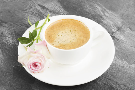 Espresso coffee in a white cup and a pink rose on a dark backgro