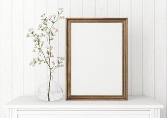 Vertical interior mock up with empty wooden frame and blooming twig on wooden wall background. 3D rendering.