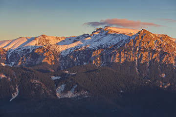 Great view of the snow capped Bucegi massif ridge in the warm colorful sunrise light, Carpathians mountains range, Romania. Spectacular hiking destinations. Romanian mountaineering attractions.