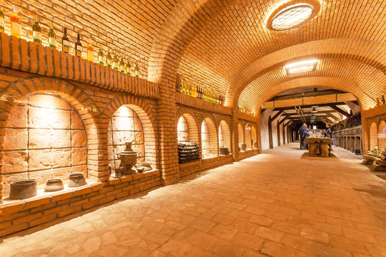 Brick walls of old wine cellar Khareba Winery with many bottles in underground cool room
