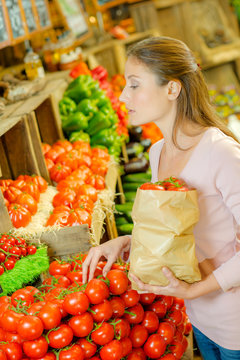 Lady  choosing tomatoes, holding paper bag