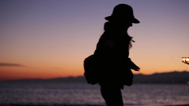 Silhouette di una ragazza sulla spiaggia al tramonto in riva al mare