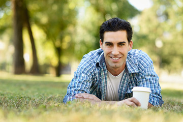 Naklejka na ściany i meble Man drinking coffee to go in an urban park