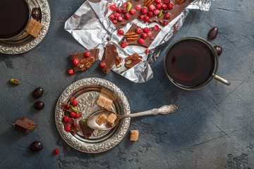 Fototapeta na wymiar Chocolate bar with dry berries on silver vintage plate, close view, dark background