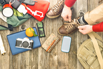 Travel man tying boots for trekking day top view of items for hiking and adventure - Active male...