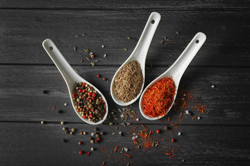 Assortment of spices in ceramic spoons on wooden background