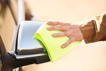 Man wiping side mirror of luxury car