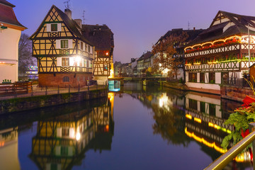 Fototapeta na wymiar Traditional Alsatian half-timbered houses with mirror reflections in Petite France during twilight blue hour decorated and illuminated at christmas time, Strasbourg, Alsace, France