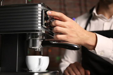 Fototapeta na wymiar Male barista making fresh espresso in coffee maker, close up