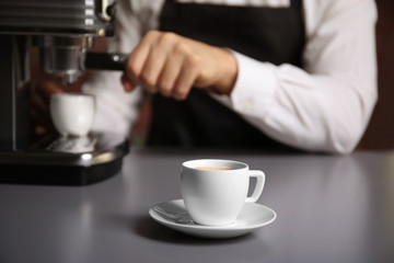 Fototapeta na wymiar Cup of fresh espresso with male barista on background