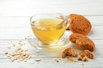 Oatmeal cookies with green tea on white wooden background