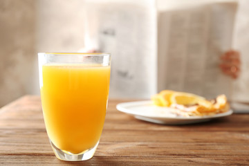Glass of fresh orange juice and breakfast on table