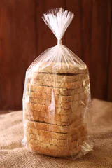 Foto op Plexiglas Sliced bread in plastic bag on wooden background © Africa Studio