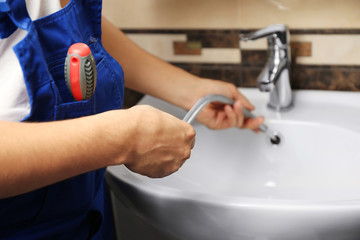 Plumber fixing water flex hose in bathroom
