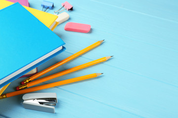 Colorful notebooks and office supplies on wooden background