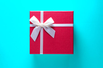 Gigt box with and white ribbon. Valentines day simbols on a blue table background