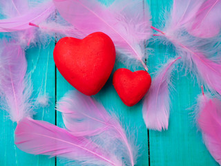 two red hearts on a blue background and the background of pink feathers, lightness and romance for...