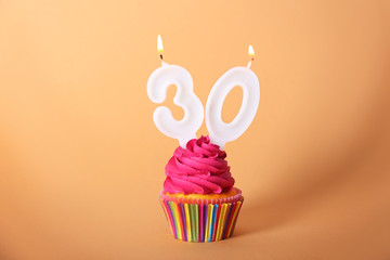Birthday cupcake with candles on color background