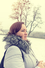 Young woman in the winter park while walking on cold winter day. Portrait close up. Coloring and processing photo with soft focus.