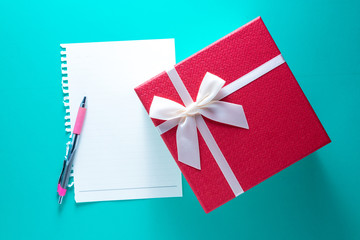 Gigt box with paper card and white ribbon. Valentines day simbols on a blue table background