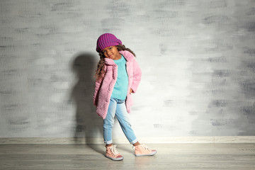 Obraz na płótnie Canvas Cute little African American girl against grey wall. Fashion concept