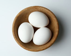 Raw eggs in bowl on white background