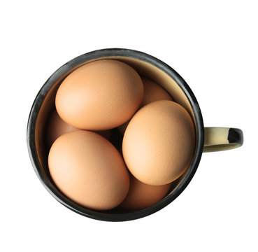 Raw eggs in enamel mug on white background
