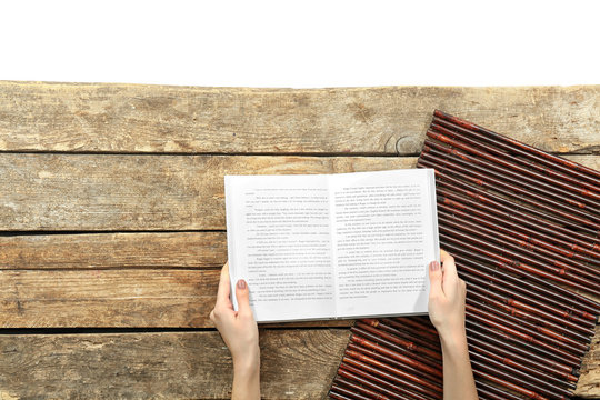 Female hands holding opened book on wooden background