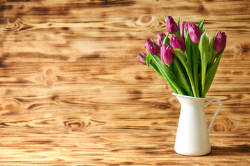 Vase with bouquet of beautiful tulips on wooden background