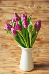 Vase with bouquet of beautiful tulips on wooden background
