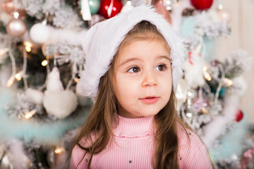 Portrait of little cute girl near Christmas tree.
