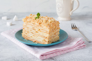 Piece of cake Napoleon on blue plate on pink textile. Russian cuisine, multi layered cake with pastry cream, close up view