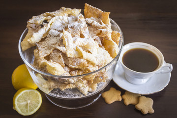 Sprinkle with powdered sugar, fried plate of shortcake dough. Dessert Polish and Lithuanian cuisine - faworki ( angel wings). Faworki in a large glass vase on a beige background.
